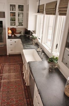 a large kitchen with white cabinets and black counter tops, along with a rug on the floor