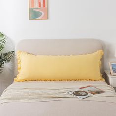 a bed with a yellow pillow on top of it next to a potted plant