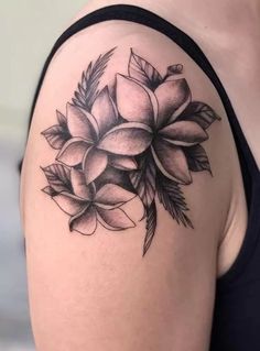 a woman's shoulder with flowers and leaves tattooed on her left arm, in black and white