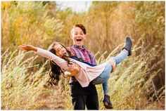 a boy and girl are holding each other in the middle of a field with tall grass