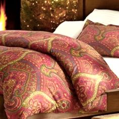 a bed sitting next to a fire place with pillows on top of it and blankets