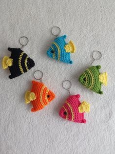 four crocheted fish keychains sitting on top of a white surface,