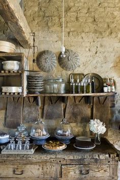 an old fashioned kitchen with lots of dishes on the counter