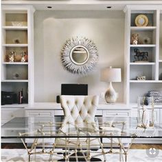 a glass table with chairs in front of white bookcases and built - in bookshelves