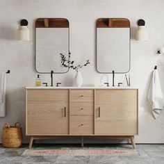 a bathroom with two sinks and mirrors on the wall next to a rug in front of it