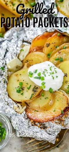 grilled potato packets with sour cream and chives on top in tin foil, ready to be eaten