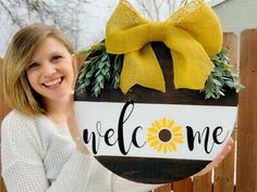 a girl holding up a welcome sign with a yellow bow on it's head