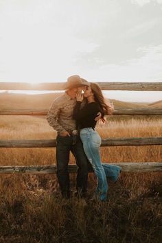 a man and woman kissing in front of a fence