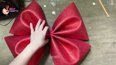 someone is tying a large red bow on the floor