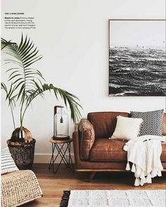 a living room with a brown leather couch and potted plants on the side table