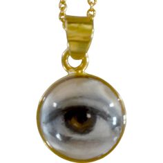 Lover's Eye pendant with an oil painting encased in gold plate over sterling with a quartz crystal cabochon which gives a magical magnifying effect, measuring 1/2" in diameter; 18" 16k gold over brass chain included. THE HISTORY: Lover's Eyes were a jewelry trend c.1785-1830 of brooches set with tiny watercolor portraits on ivory. Since they were cropped to eyes, they were in many ways more direct and intimate than traditional miniature portraits; but also because they were just eyes, they were often used as daring public testimonies of clandestine love affairs with mystery lovers. THE SETTINGS: This piece is part of the collection of contemporary minimalist settings which juxtapose this historical jewelry tradition with clean, modern lines for a subtle effect that's easy to wear. Lover's Eye Necklace, Mystical Engraved Gold Jewelry, Gold Mystical Sterling Silver Necklace, Mystical Sterling Silver Gold Necklace, Mystical Gold Engraved Necklace, Mystical Engraved Gold Necklace, Mystical Gold Charm Necklace Gift, Spiritual Gold Cabochon Necklace, Gold Spiritual Necklace With Cabochon