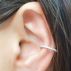 a woman's ear with a single diamond ring on it