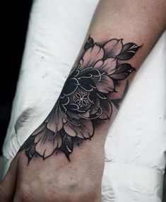 a woman's hand with a black and white flower tattoo on it