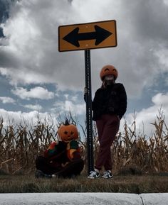 a person in a pumpkin costume standing next to a pole with an arrow sign on it