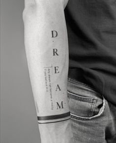 a man with a black and white tattoo on his arm that says dream in cursive writing