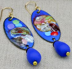 Earrings are 1 of a kind! Beautiful artisan enameled copper abstract mis-matched charms abound with brilliant color!  These charms are handpainted and the design is 3-dimensional....some areas are raised, some more than others. I added Czech glass teardrop beads sitting atop fancy ball-head brass headpins  to bottom of charms.   These earrings will brighten up your day and bring a smile to faces that see them!  I think you are going to love wearing them! Earrings are just under 3 inches in lengt Abstract Enamel Jewelry, Artistic Enamel Dangle Earrings, Artistic Enamel Earrings Nickel-free, Hand Painted Artsy Enamel Earrings, Hand Painted Enamel Artsy Earrings, Artistic Enamel Earrings With Artistic Design, Artistic Enamel Earrings, Artsy Blue Enamel Jewelry, Artistic Design Enamel Earrings