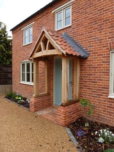 a brick house with a blue front door and small wooden window frames on the side