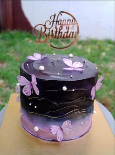 a purple and black cake with butterflies on it