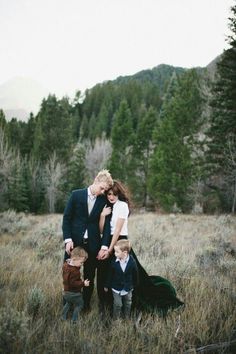 a family is posing for a photo in the grass with mountains in the back ground