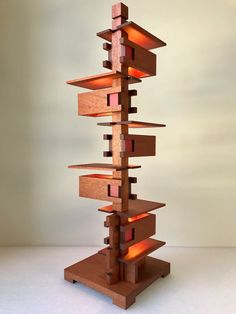 a tall wooden sculpture sitting on top of a white table next to a light bulb