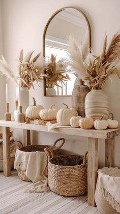 a table topped with lots of white pumpkins next to a vase filled with dry grass