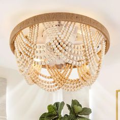 a white chandelier hanging from the ceiling in a room with potted plants