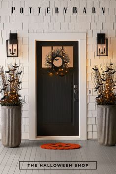 two planters with wreaths and lights on the front of a house that is decorated for halloween