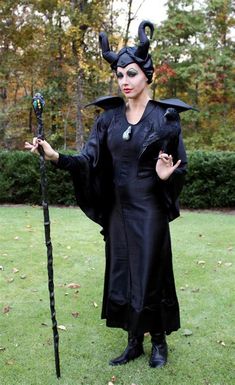 a woman dressed up as maleficent holding a wand and wearing a black dress