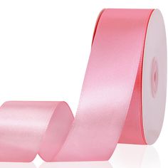 a roll of pink satin ribbon on a white background