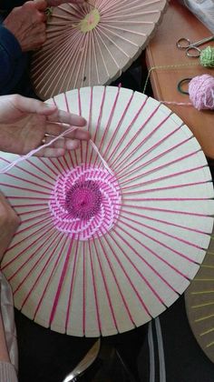 the woman is working on her craft with pink and white parasols in front of them