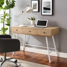 a laptop computer sitting on top of a wooden desk next to a chair and potted plant