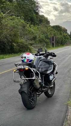 the motorcycle is parked on the side of the road next to the grass and trees