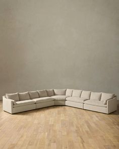 a large sectional couch sitting on top of a hard wood floor next to a wall