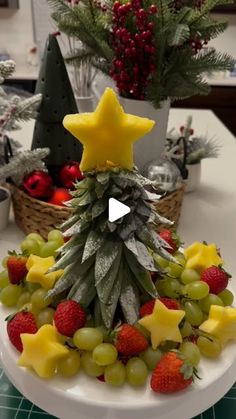 a christmas tree made out of fruit on top of a white plate with pineapples, grapes and strawberries