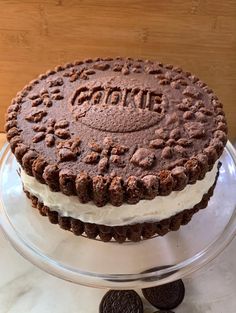 an oreo cookie cake with white frosting and chocolate cookies on the side sitting on a glass platter