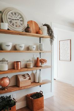 the shelves are filled with pots, bowls and vases on them in front of a clock