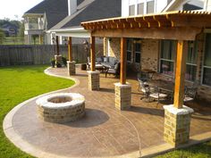 a patio with an outdoor fire pit and seating area in the back yard, surrounded by grass