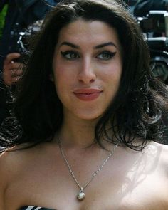 a woman wearing a black and white striped dress posing for the camera with her hand on her hip