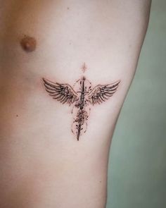 a tattoo on the side of a woman's stomach with a cross and wings