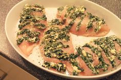 a white plate topped with slices of meat covered in spinach