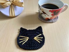 a crocheted cat coaster next to a cup of coffee