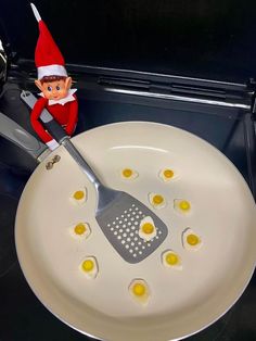 an elf is cooking eggs in a frying pan with a spatula on the side