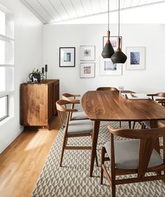 a dining room table with chairs and pictures on the wall