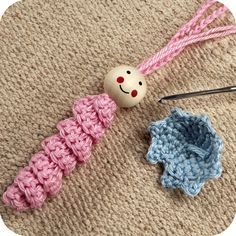 two crocheted items are laying on the floor next to each other, including a ball of yarn and a knitting needle