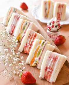 several slices of cake sitting on top of a wooden cutting board next to strawberries