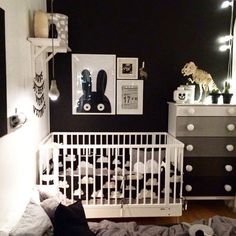 a white crib in a black and white room with pictures on the wall above it