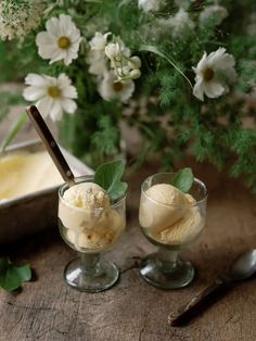 two glasses filled with ice cream next to flowers