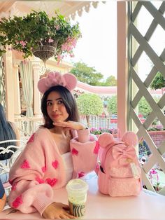 a woman sitting at a table wearing pink sweaters