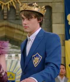 a young man wearing a blue suit and gold crown