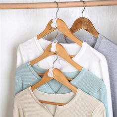 four sweaters are hanging on a wooden hanger